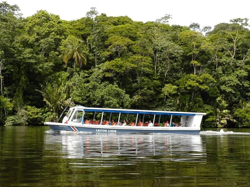 Passenger boat crossing a wide rainforest canal in Limón